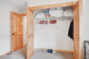 Ein begehbarer Kleiderschrank mit Holztüren, ein Regal für gefaltete Kleidung und ein Paar Schuhe auf dem Boden.