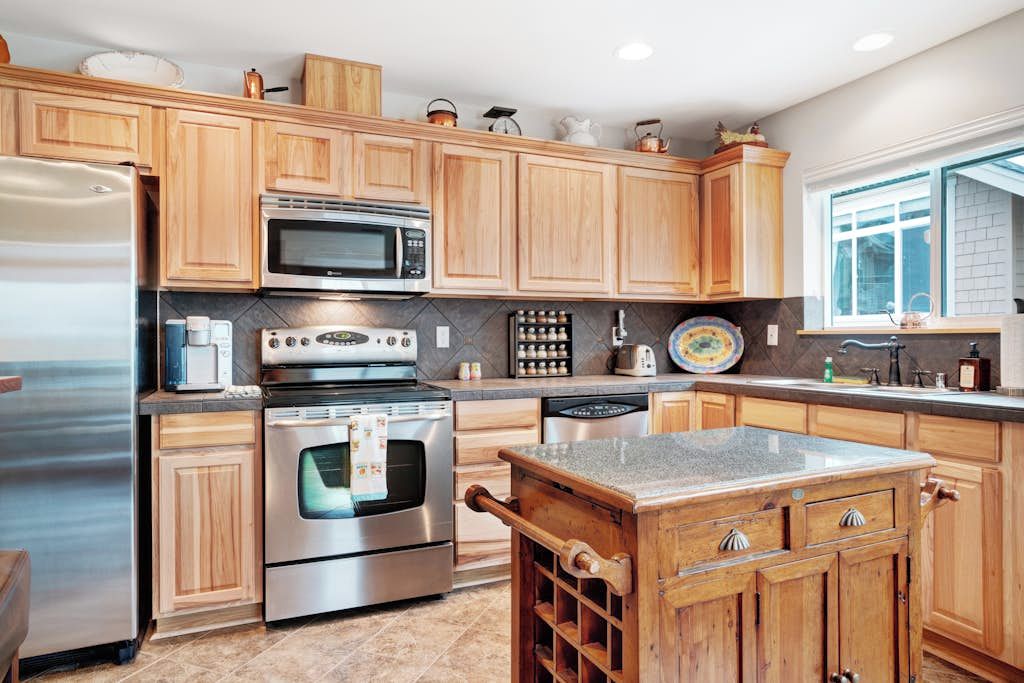 A modern kitchen with wooden cabinets, stainless steel appliances, and a granite countertop.