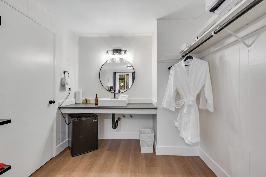 A modern bathroom with a white sink, mirror, and towel rack.