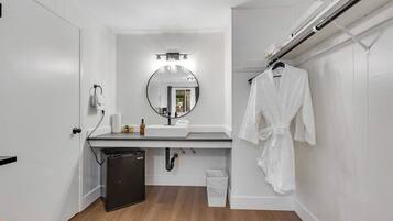 A modern bathroom with a white sink, mirror, and towel rack.