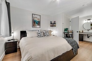 Une chambre à coucher moderne avec un lit, des tables de chevet, une commode, un miroir et une étagère remplie de livres.