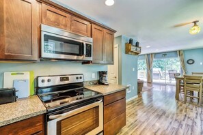 A kitchen with wooden cabinets, stainless steel appliances, a granite countertop, and a dining area with a table and chairs.