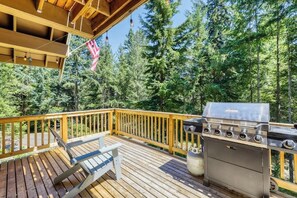 A wooden deck with a barbecue grill and a flag.