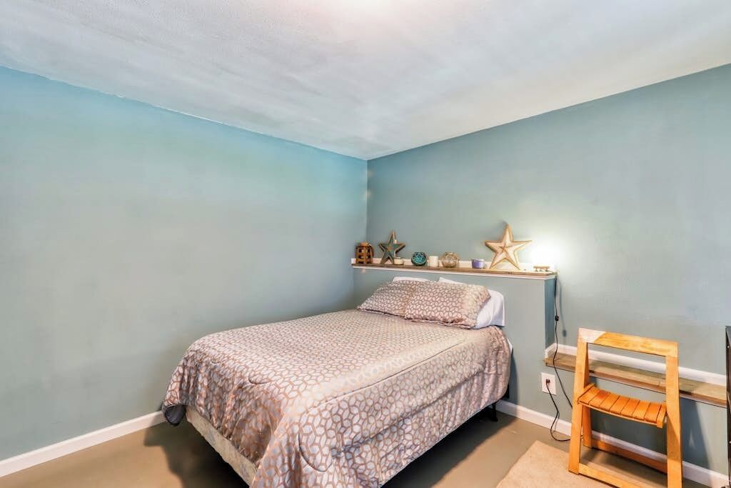 Une chambre à coucher avec un lit, une étagère ornée d’objets décoratifs et un luminaire en forme d’étoile de mer.
