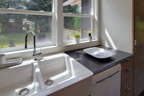 A kitchen with a double sink, a window with a view of the backyard, and a dish on the counter. - 2BR charmer near the lake with large yard & bike (Renton)