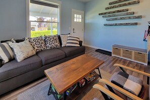 A living room with a sofa, a coffee table, and a chair. There is a door and a window in the background. - 2BR charmer near the lake with large yard & bike (Renton)