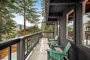 A balcony with a view of trees and mountains, a wooden railing, and two green chairs. - 4BR - Sauna - WoodStove - Balcony - Firepit - Washer Dryer (Snoqualmie Pass)