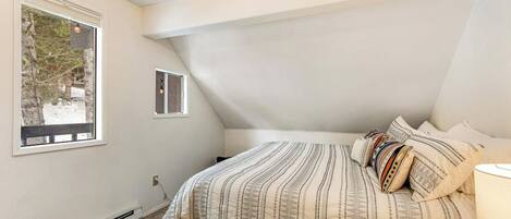Ein Schlafzimmer mit Bett, Fenster und Heizung.