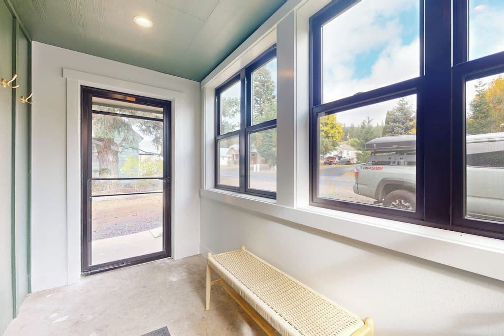 A room with a bench, large windows, and a door leading outside.