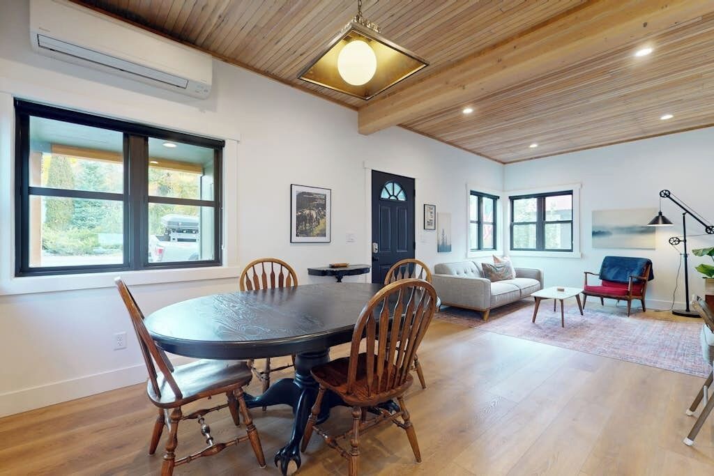 A dining area with a round table and chairs, a living room with a sofa and a coffee table, and a door with a window.