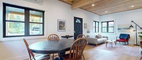 A dining area with a round table and chairs, a living room with a sofa and a coffee table, and a door with a window.