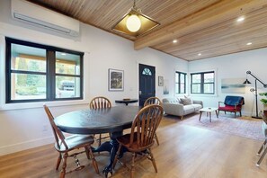 A dining area with a round table and chairs, a living room with a sofa and a coffee table, and a door with a window. - Cabin 3BR - Foosball - Gas Grill - Kids Games (Ronald)