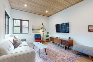 Una sala de estar con un sofá, una mesa de centro, un televisor y una planta.