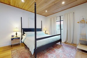 A four-poster bed with a dark frame, a wooden ceiling, and a patterned rug. - Cabin 3BR - Foosball - Gas Grill - Kids Games (Ronald)