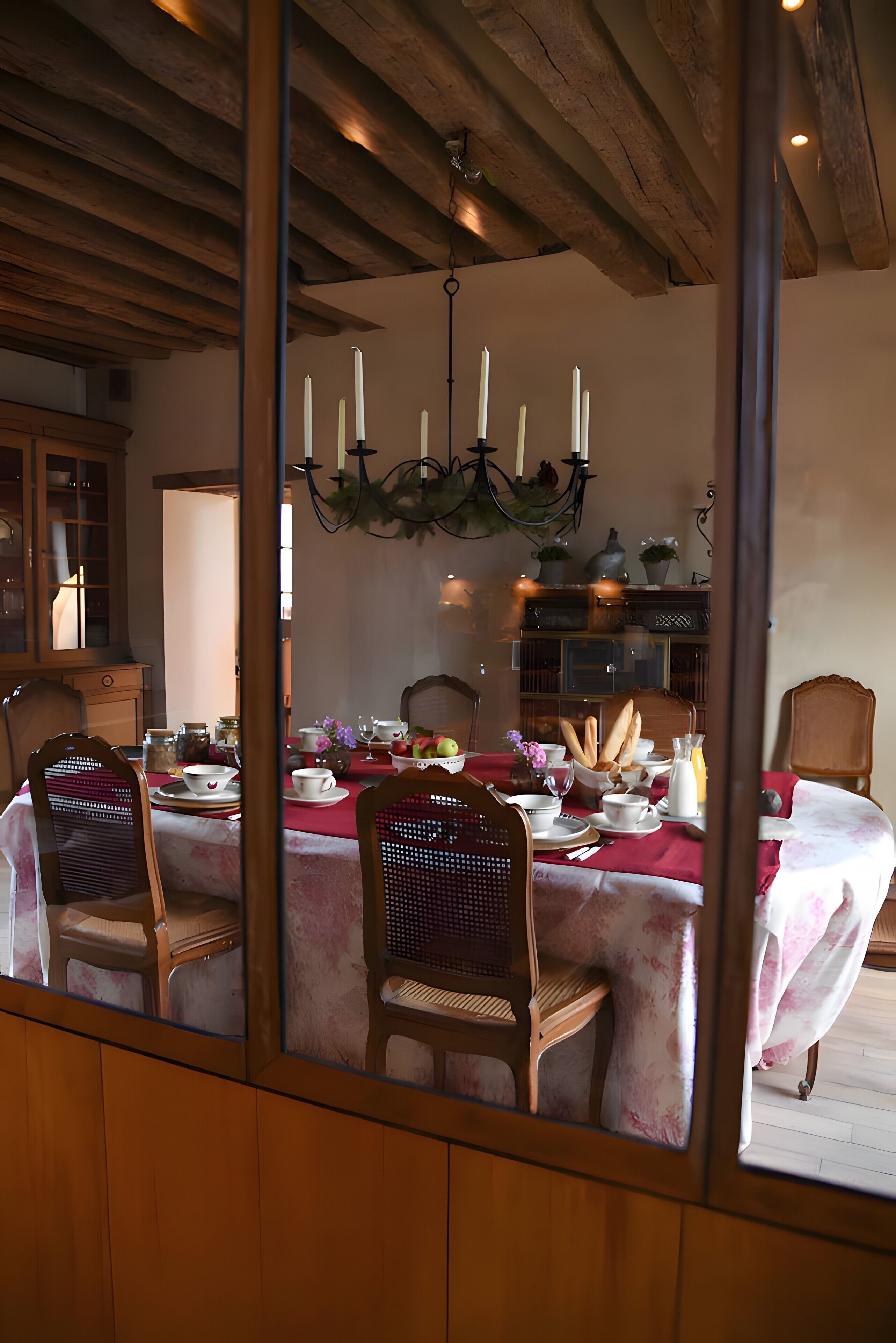 A dining area with a wooden table set for a meal, chairs, and a chandelier.