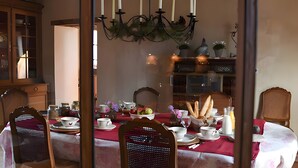A dining area with a wooden table set for a meal, chairs, and a chandelier.