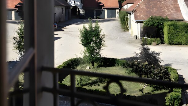 A courtyard with buildings, a clear sky, and a view through a window with a decorative frame.