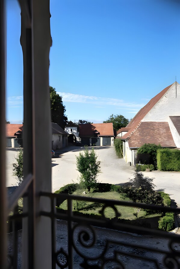 A courtyard with buildings, a clear sky, and a view through a window with a decorative frame.