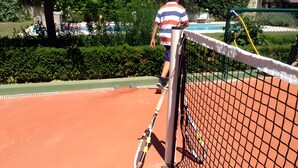 A tennis court with a net, a tennis racket, and a ball.
