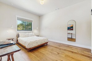 A bedroom with a bed, a window, a mirror, and a table with books. - 3 BR Home with loft, game room, fire table & trails (Cle Elum)