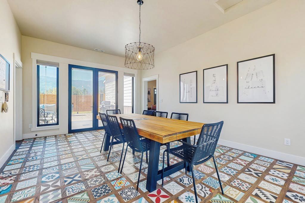 A dining area with a wooden table and chairs, patterned floor tiles, and framed artwork on the walls.