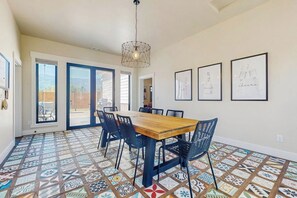 Un comedor con mesa y sillas de madera, baldosas de suelo estampadas y cuadros en las paredes.