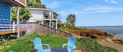A coastal property with a deck, outdoor seating, and a view of the sea.