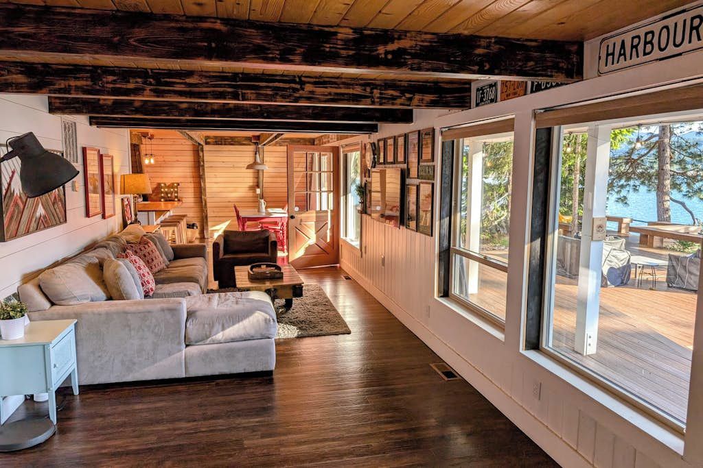 A cozy interior with a wooden ceiling, a sofa set, and large windows overlooking a deck.