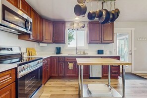 Una cocina con armarios de madera, electrodomésticos de acero inoxidable y un colgador para ollas.
