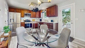 Una cocina moderna con armarios de madera, electrodomésticos de acero inoxidable y una mesa de comedor de vidrio con sillas.