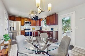 Una cocina moderna con armarios de madera, electrodomésticos de acero inoxidable y una mesa de comedor de vidrio con sillas.