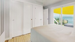 Un dormitorio con cama, un ventanal grande con persiana amarilla y vistas al exterior.