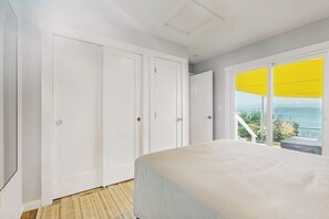 Un dormitorio con cama, un ventanal grande con persiana amarilla y vistas al exterior.