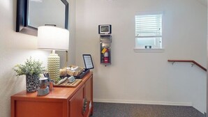 A hallway with an exit sign, a clock, a fire extinguisher, and a window. - 1BR Hotel Room right in Downtown Port Townsend (Port Townsend)