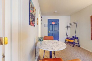 A room with a round table, a blue door, a coat rack, and a hanging plant.