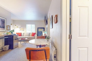 A compact living space with a kitchenette, a dining area, and a seating area with a sofa and chairs.