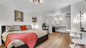 Une chambre moderne avec un grand lit, des tables de chevet, un bureau et un miroir rond.