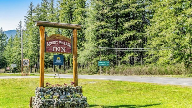 Une enseigne pour le Mount Walker Inn, avec un socle en pierre et un poteau en bois.