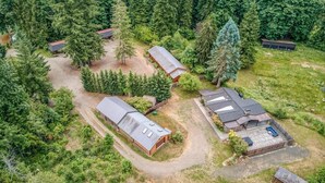 Une vue aérienne d’une propriété comprenant plusieurs bâtiments, entourée d’une forêt dense.