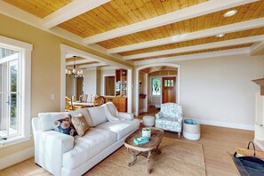 A spacious living room with a white sofa, a patterned armchair, and a coffee table. - 2BR  with loft soundfront retreat with mtn & city views (Bainbridge Island)