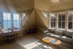 A room with a desk, chair, and a sofa with a view of the water. - 2BR  with loft soundfront retreat with mtn & city views (Bainbridge Island)