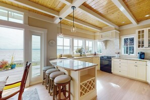 A kitchen with a large island, wooden ceiling, and a view of the ocean. - 2BR  with loft soundfront retreat with mtn & city views (Bainbridge Island)