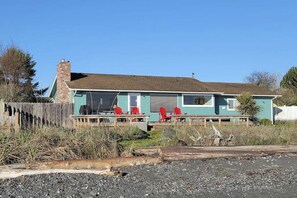 A single-story building with a porch, a chimney, and a garage door. - 3 BR beachfront cabin with private hot tub (Sequim)