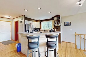 A kitchen with a central island, two bar stools, wooden flooring, and recessed ceiling lights. - Dog-friendly house with enclosed yard (Port Orchard)