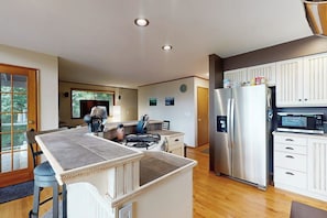 A modern kitchen with a central island, stainless steel appliances, and a dining area with a view. - Dog-friendly house with enclosed yard (Port Orchard)