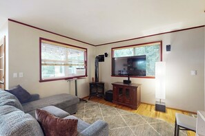 Ein Wohnzimmer mit einem großen Flachbildfernseher, einem Kamin und einem Sofa.