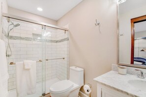 Ein Badezimmer mit Duschkabine, Toilette, Waschbecken und Spiegel.