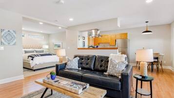 A modern living room with a leather sofa, a wooden coffee table, and a dining area with wooden chairs.