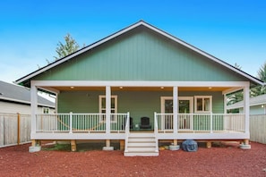 A single-story house with a green exterior, a covered porch with white railings, and a small front yard with mulch. - Elegant 3BR Dog Friendly - Deck - Washer Dryer (Westport)