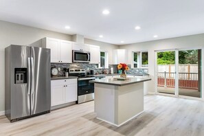 A modern kitchen with stainless steel appliances, a central island, and a view to the outside. - Elegant 3BR Dog Friendly - Deck - Washer Dryer (Westport)